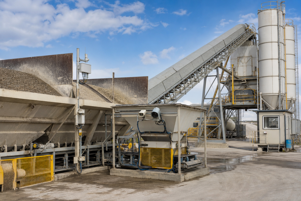 Concrete batching plant with aggregate bins covered conveyor weighing hopper moisture sensor cabinets cement silos and organized yard access