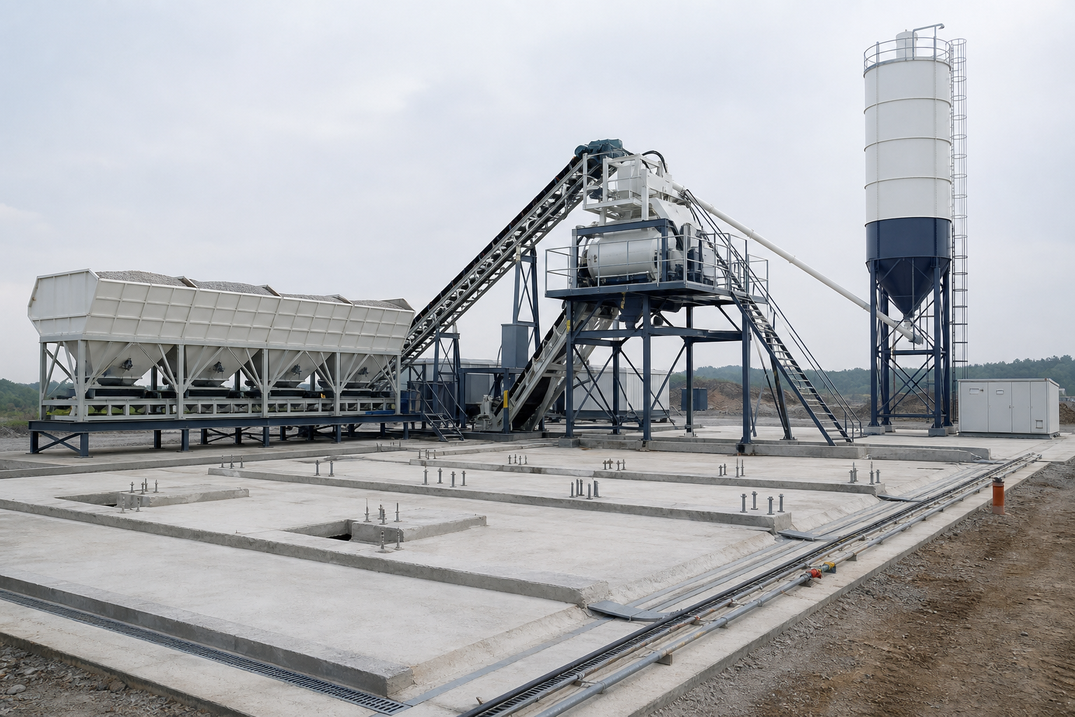 Mobile concrete batching plant on prepared concrete foundation pads with aggregate bins belt conveyor cement silo drainage channels anchor bolts and utility routes