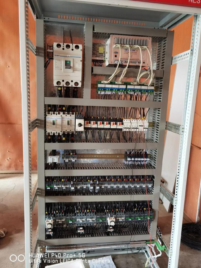 Concrete batching plant with electrical control cabinets cooling fans cable trays cement silos aggregate conveyor and mixer tower